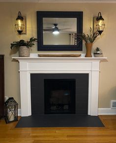 a fireplace with a mirror above it and some plants on the mantels next to it