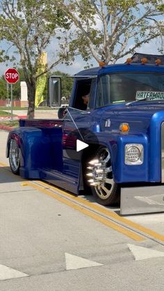 a large blue truck parked on the side of a road next to a stop sign