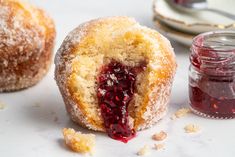 a jelly filled doughnut with powdered sugar and jam on the table next to it