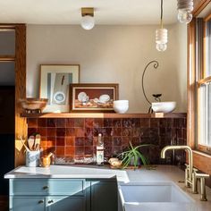 a kitchen sink sitting under a window next to a counter top with dishes on it