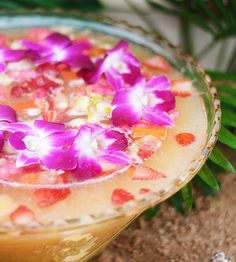 a drink with flowers in it sitting on top of a glass bowl filled with liquid