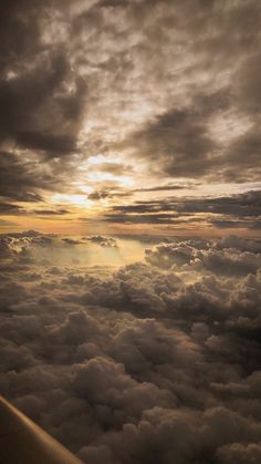 the view from an airplane looking down on clouds and sun shining in the sky above