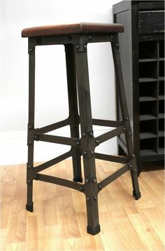 a wooden stool sitting on top of a hard wood floor next to a wine rack