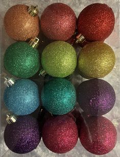 christmas ornaments are arranged in a box on the snow covered ground, including red and green ornament balls