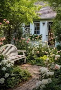 a white bench sitting in the middle of a garden next to flowers and plants on either side of a house