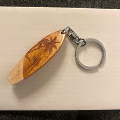 a wooden keychain with an engraved surfboard on it's front end