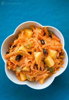 a bowl filled with carrots and raisins on top of a blue table