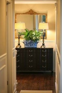 an entry way with a mirror, lamp and dresser in it's centerpiece