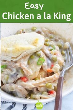 a bowl filled with chicken and peas next to a fork on top of a table