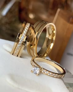 two gold wedding rings with diamonds on them sitting on top of a white towel next to each other