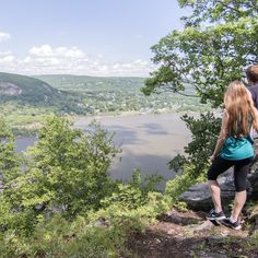 two people standing on the edge of a cliff overlooking a lake