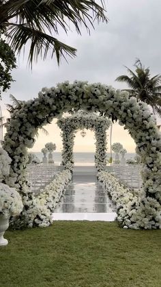 an outdoor wedding setup with white flowers and greenery on the grass, surrounded by palm trees