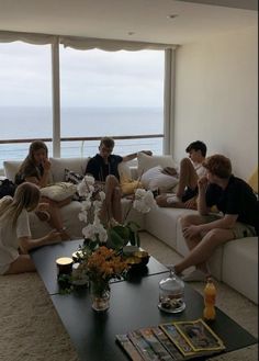 a group of people sitting on top of a couch in a living room next to a window