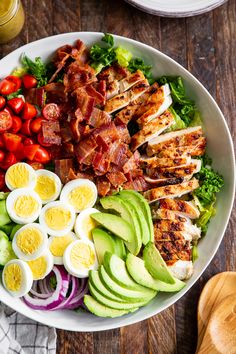 a salad with hard boiled eggs, bacon, tomatoes and avocado in it