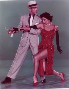 a man in a suit and tie dancing with a woman wearing a red sequin dress