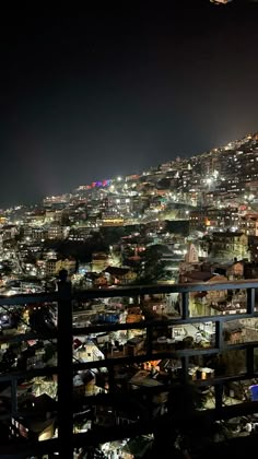 the city lights shine brightly in the night sky from an elevated rooftop area with buildings on both sides