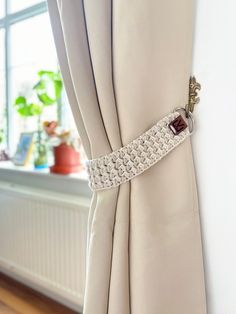 the curtain is pulled back with a crochet design on it, and has a button at the end