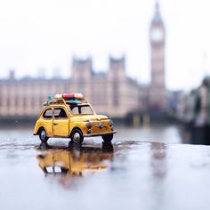 a toy car with luggage on top is parked in front of a building and clock tower