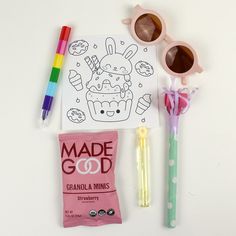 the contents of an adult coloring book, sunglasses, and candy are laid out on a white surface