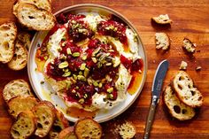 a plate with bread, cranberry sauce and pistachios on it