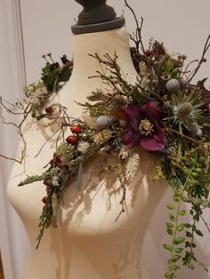 a white mannequin with flowers and greenery on it