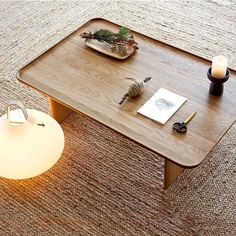 a coffee table with a lit candle and some books on it next to a lamp