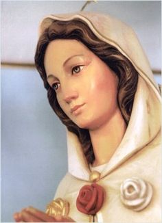 a statue of the virgin mary holding a rose in her right hand and wearing a white coat