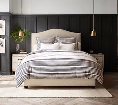 a bedroom with black and white striped bedding, two lamps and a rug on the floor