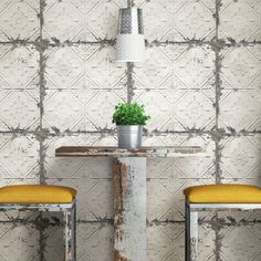 two yellow stools sit in front of a table with a potted plant on it