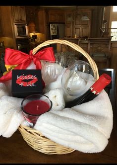 a basket filled with wine glasses, candles and a red bow on top of it