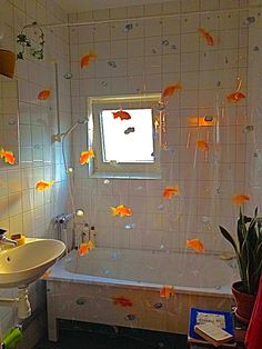 a bath room with a tub a sink and some goldfish on the wall in it