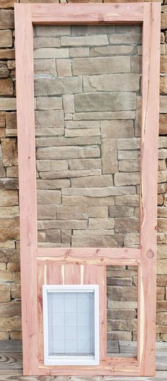 a wooden frame sitting on top of a table next to a stone wall with a window