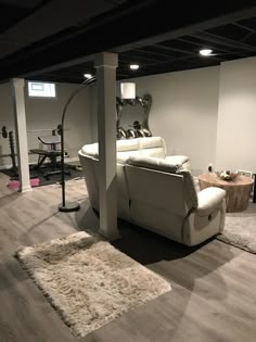 a living room filled with furniture and a white rug on top of a hard wood floor