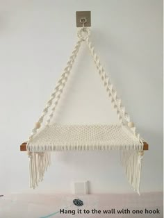 a white macrame hanging on a wall with a quote about hang it to the wall with one hook