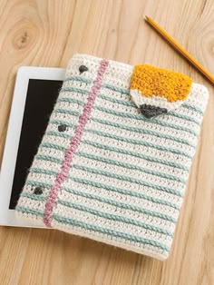 an ipad case with a crochet pattern on it and a pencil next to it