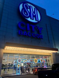 an exterior view of a city bagger store at night with people walking in front