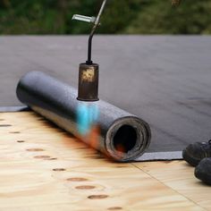 a piece of metal on top of a wooden floor next to a roll of paper