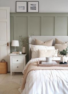 a white bed sitting next to a nightstand with two pictures on the wall above it