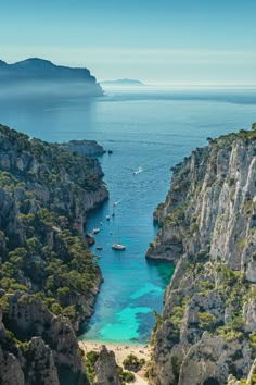 an aerial view of boats in the water near rocky coastlines and cliffs with trees on either side