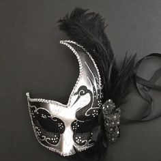 The swan-inspired black/silver mask for women has arching feathers. Silver Masquerade Mask For Carnival Theater, Silver Masquerade Mask For Theater And Carnival, Silver Masquerade Mask For Mardi Gras Theater, Black Feathered Masquerade Mask For Costume Party, Black Feathered Masquerade Mask, Mask Ball Party, Masquerade Mask Black, Silver Masquerade Mask, Mask Ball