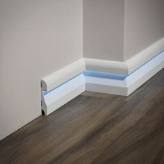 the corner of a room with wood flooring and white walls