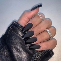 a woman's hand with black stiled nails and ring on her finger, holding a