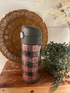 a coffee cup sitting on top of a wooden table next to a potted plant