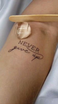 a person with a tattoo that says never give up on their arm and the word is written in cursive ink