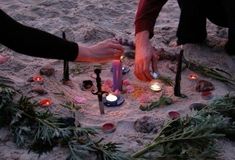 two people placing candles in the sand