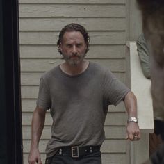 a man in grey shirt standing next to a door