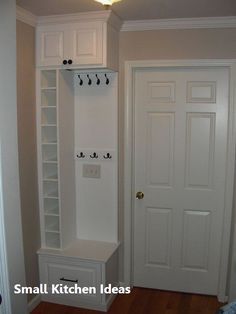 a white coat rack in the corner of a room next to a door with hooks on it