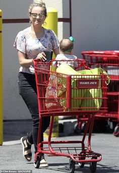 a woman pushing a baby in a shopping cart