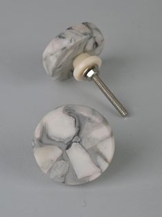 a pair of white marbled knobs on a gray surface with a screw in the middle