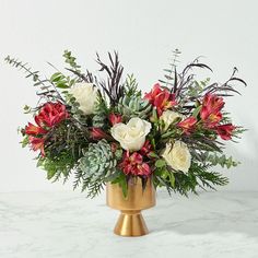 a gold vase filled with white and red flowers